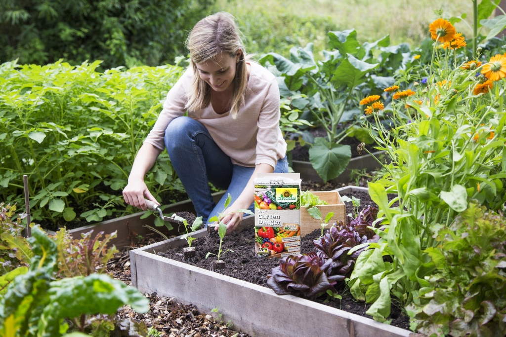 Una mujer abona las plantas de su jardín